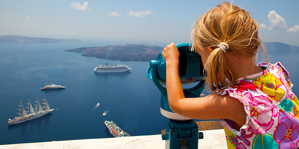 Girl looking at cruise ships with binoculars in Thira Santorini Greece